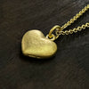 side photo of our solid 925 sterling silver heart pendant with a 24k gold vermeil finish showing the hallmark on the side of the pendant.