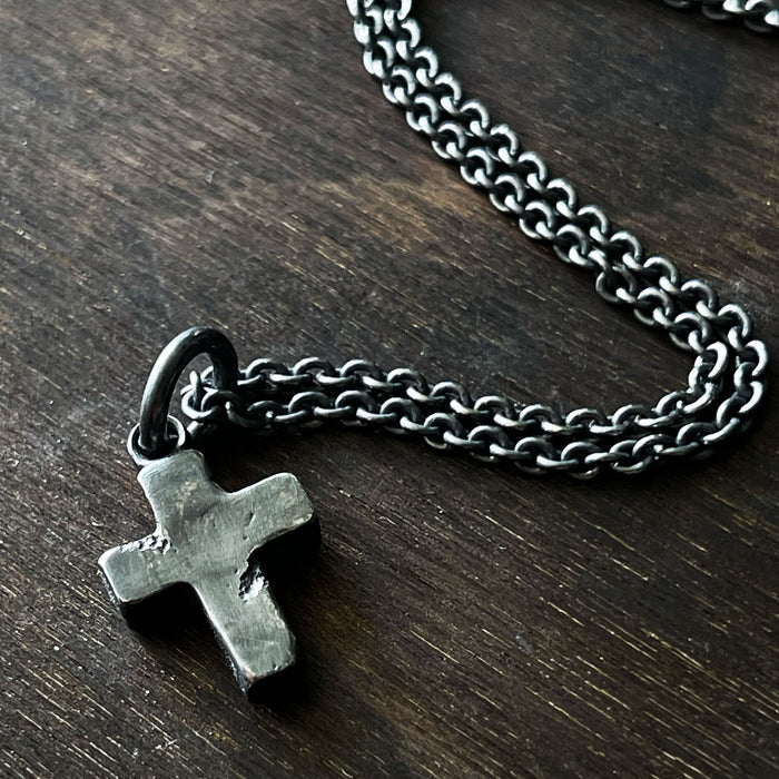 rustic cross pendant shown with trace chain in an oxidised silver finish.