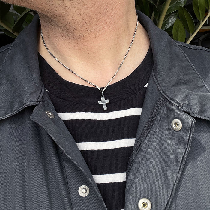 alternative photo of the rustic cross pendant shown on a male model.