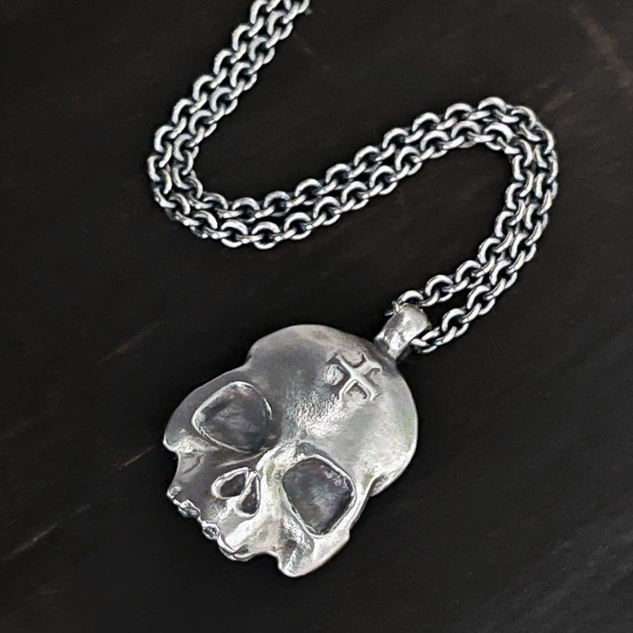 double-sided flat skull pendant showing a cross on the skull in sterling silver.