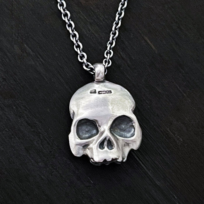 detail photo of the hallmark on this this double-sided flat skull pendant by jewel thief Brighton.