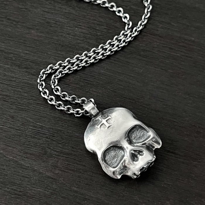 alternative photo of this double-sided flat skull pendant showing a cross on one side of the skull.