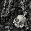 close up detail photo  of this double-sided flat skull pendant showing the trace chain necklace.